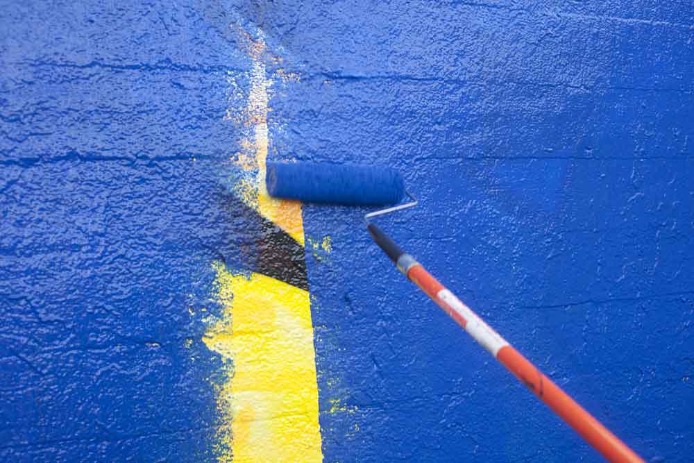 Maľovanie steny farbou, ktorá prekrýva graffiti